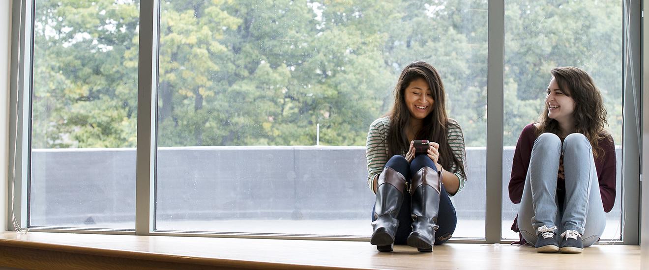 two students sitting by a window on campus